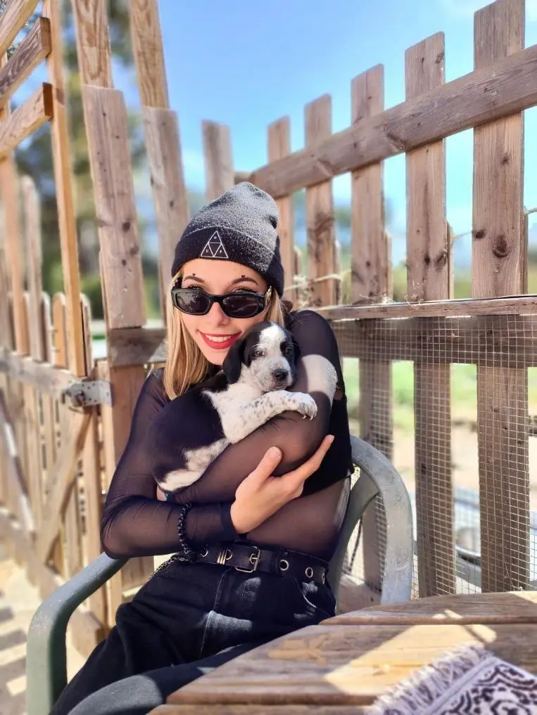 Lela Soler, éducatrice canine à Valbonne, tenant un chiot devant la palissade d'un refuge